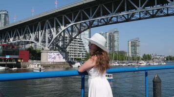 Greenville Island girl on the waterfront A woman tourist in a white hat and dress stands near the bridge video