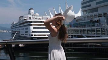 Cruise ship in the background travel ride on the sea ocean Young girl in a white hat on the waterfront in Canada Canada Place Vancouver Downtown video