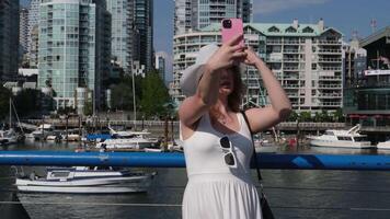 Take a selfie Greenville Island girl on the waterfront A woman tourist in a white hat and dress stands near the bridge video