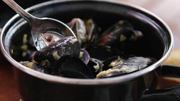 Sea mussels cooked with herbs sprinkled with dill rotating slow motion, a person picks up a steamed mussel from a plate. video