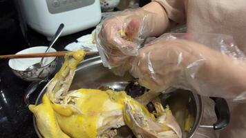 Vietnamese domestic chicken boil the yellow chicken in water, tear it into pieces, add herbs and rice Dinner in Asia in Ho Chi Minh City, woman preparing family dinner wearing disposable gloves video