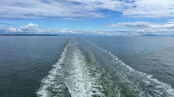 a trail on the water leaving itself ship a huge liner a cruise ship you can see the seething water beautiful sky deep ocean around nature and the ship is sailing away Canada to Vancouver Island Ferry video