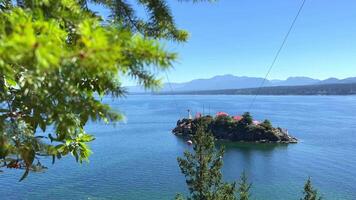 cromada ilha pequeno perto Vancouver ilha tem branco casas com vermelho telhados e uma solteiro farol Visão a partir de Denman ilha para tesão ilha pacífico oceano conífero árvores azul mar video