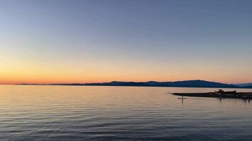 puesta de sol en el mar usted lata ver personas quien son kayak o surf pero ellos son sólo puntos en vasto Oceano brillante naranja horizonte línea muestra ese el Dom tiene conjunto calentar antecedentes sombras para ninguna texto viaje video