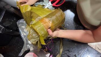 Vietnamese New Year rice cake made of sticky rice and colorful stripes of women's hands unwinding on the festive table Vietnamese Asian food video