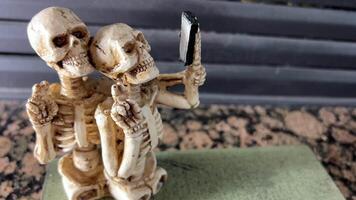 halloween decoraties grap skeletten zonder poten nemen een selfie kijken Bij een mobiel telefoon ze glimlach met allemaal hun tanden en tonen twee vingers omhoog net zo als Victor plaats voor tekst Aan achtergrond van haard video