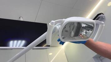 profissional dental clínica dental escritório médico mão voltas em a luz sobre quadro, Armação pode estar visto só trocando em toque tela colocar seu mão dentro a fundo televisão e ar condicionamento branco teto video