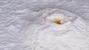 bellissimo caduta uova in Farina caduta nel uno posto nel uno imbuto Farina disperde piace un' vulcano e lago cucinando per cottura al forno lento movimento pieno HD 240 fps delizioso pasticcini avvicinamento spazio per testo video