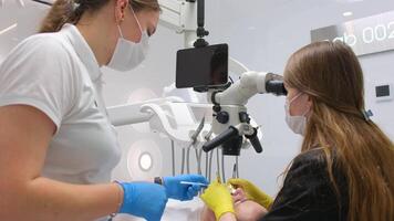 dentist doctor and nurse treat teeth to a patient using a microscope Female patient opening her mouth under the dental microscope and a professional dentist holding tools video