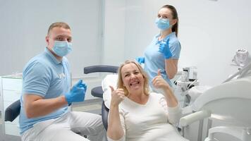 Dental Büro zufrieden geduldig zeigen Daumen oben groß Klasse sie gefallen das Bedienung Neu Technologien maskiert Arzt und Assistent sind ebenfalls glücklich mit das Ergebnis von Arbeit Lächeln Freude Zahnarzt Blau Kleider video