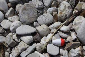 pebbles on the beach and a red and white float photo