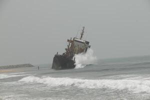 shipwreck against which the waves crash, cotonou, benin photo