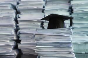 un graduación soltero gorra en un apilar de papel, nuevo graduado trabajo caza concepto. foto