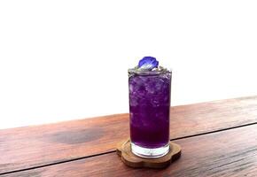 isolated glass of Butterfly Pea Lime Juice on wooden background It's a herbal drink. Cold drink menu that is easy to make, delicious and refreshing. photo