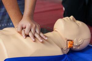 asiático joven rojo cruzar estudiantes práctica cpr con un maniquí durante un formación curso en Ayudar pacientes quien son muriendo a respirar espalda a respiración. o respiración lata circular normalmente. foto