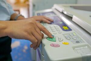 The office secretary presses the button to start the document copying machine to have another copy of the document stored in a file as evidence. photo