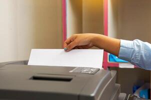 The secretary uses a copier to copy documents into a file to store in a system. soft and selective focus. photo