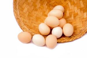 Organic chicken eggs in a bamboo basket on a white background are eggs that come from chickens raised on organic food. They do not contain toxic residues that are harmful to the body. photo