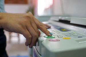 The office secretary presses the button to start the document copying machine to have another copy of the document stored in a file as evidence. photo