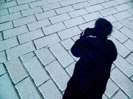 silhouette shadow of a girl with a camera on the background of road masonry photo