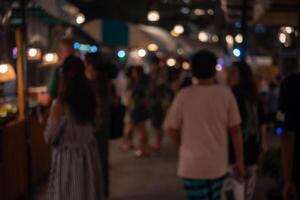 abstract blurred festival food market night light bokeh background. People walking travel street food and stalls photo