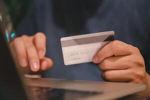 Man holding credit card and electronic computer laptop for online shopping, digital payment concept. Web app check balance client banking customer transaction photo