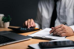 Professional calculating finances on a calculator with documents, laptop and smartphone on desk photo