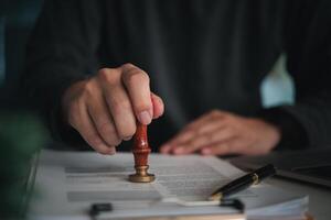 Focused individual placing a seal on an official document with red wax stamp in a professional setting photo