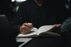 man hands with pen writing on notebook in the office.learning, education and work.writes goals, plans, make to do and wish list on desk. photo