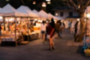 abstract blurred festival food market night light bokeh background. People walking travel street food and stalls photo