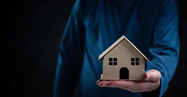 Close-up of hands holding a wooden house model. Real estate agent offer house business sale property offer contract purchase photo