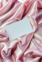 Minimalist aesthetic mockup of white blank A5 envelope on pink silk fabric. photo