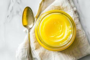 Top view, jar of ghee on a linen napkin with a spoon. photo