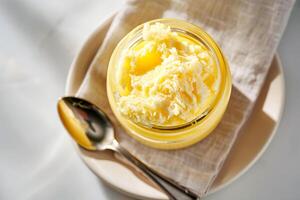 Top view, jar of ghee on a linen napkin with a spoon. photo