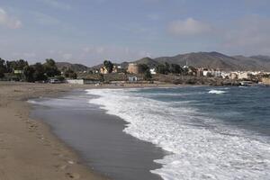 bay of villaricos, rough sea, beach, village and mountains at the background photo