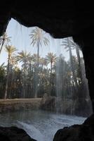 look through a whole in the rocks through the waterfall on the trees photo