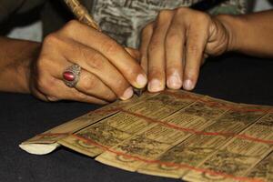 Making a balinese calender with bamboo and charcoal, Tenganan a traditional balinese village, Balinese Aga the original inhabitants of the island, photo