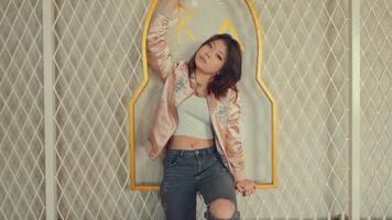 Stylish young woman posing with a playful attitude in front of a textured wall with geometric patterns. video