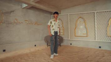 Man in casual attire standing in an unfinished room with exposed walls and floor, contemplating interior design video