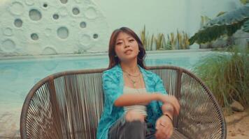 Thoughtful young woman sitting alone on a metal bench with a contemplative expression, wearing a blue shirt video