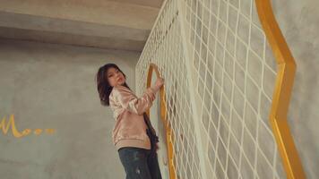 mujer en rosado vestir alpinismo un escalera en contra un blanco embaldosado muro, representando crecimiento o desafío. video