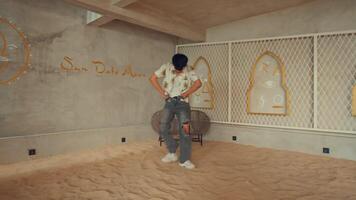 Man sitting on chair in unfinished room with exposed walls and sandy floor, looking at camera. video