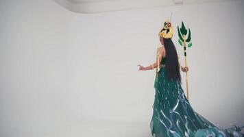 élégant la personne dans une mascarade costume avec une oiseau masque et une long, écoulement vert robe posant contre une blanc Contexte. video