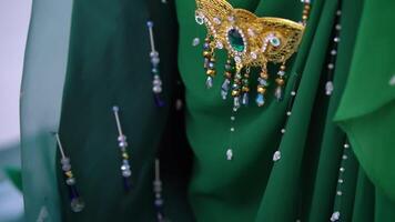 Close-up of an intricate green traditional costume with bead work and a golden headpiece. video