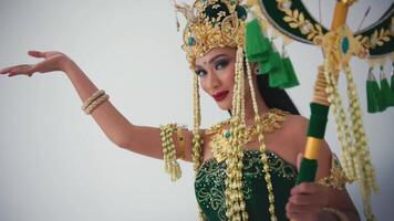 vrouw in traditioneel balinees danser kostuum met gouden hoofdtooi en groen kleding, het uitvoeren van met elegant hand- gebaar. video