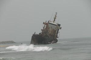 shipwreck against which the waves crash, cotonou, benin photo