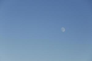 Luna brilla en un brillante azul cielo foto