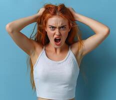 Frustrated young redhead woman yelling with hands in hair photo