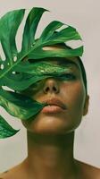 Portrait of a woman partially covered by a green tropical leaf photo