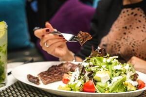 Woman Eating Salad With Fork at Outdoor Restaurant photo